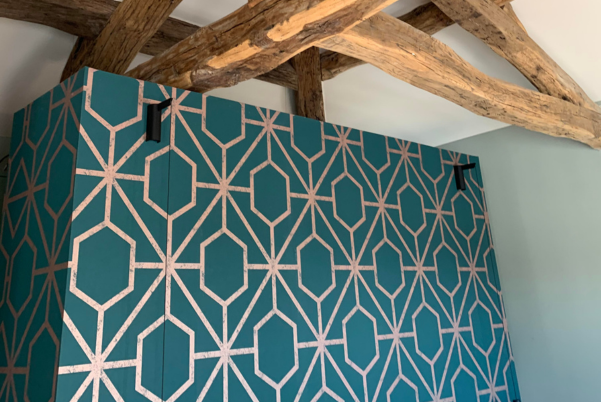 Gros plan sur une r�alisation de peinture et de d�coration murale avec un motif g�om�trique bleu et cuivre sous des poutres en bois apparentes par un peintre d�corateur � Gardanne